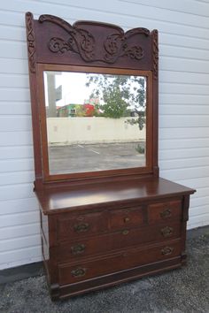 an antique dresser and mirror in front of a white building