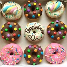 a box filled with lots of donuts covered in frosting and sprinkles