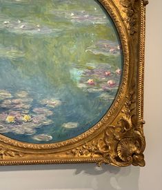 an ornate gold frame with water lilies on it in front of a white wall