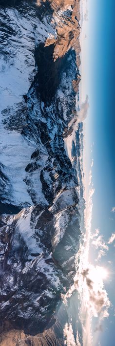 an aerial view of snow covered mountains and water