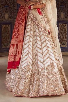 Ivory attached cancan lehenga with gold dabka, sequin, bead, red resham, french knots embroidery in chevron pattern. Paired with sweetheart neck padded blouse. Comes with cutwork border embroidered ivory dupatta and red bandhani woven dupatta. - Aza Fashions White Cutdana Wedding Dress, Ceremonial White Dress With Dupatta, White Anarkali Gown For Ceremonial Occasions, Off White Cutdana Wedding Dress, White Floor-length Traditional Wear For Ceremonial Occasions, White Floor-length Traditional Wear For Ceremonial Events, White Floor-length Traditional Ceremonial Wear, White Ceremonial Gown With Traditional Drape, White Cutdana Wedding Gown