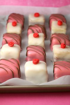 some pink and white desserts are on a tray with red berries in the middle