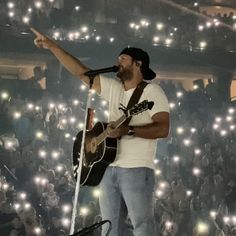 a man standing on top of a stage holding a guitar