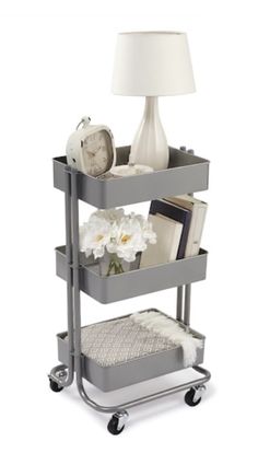 a metal cart with two trays on it and a lamp in the corner next to it