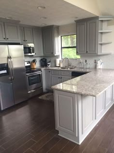 a large kitchen with stainless steel appliances and wood flooring is pictured in this image