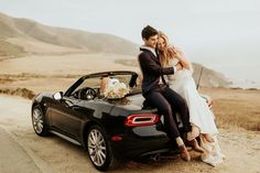 a bride and groom sitting on the back of a convertible car