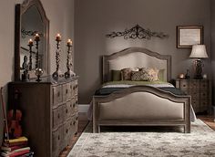 a bed room with a neatly made bed next to a dresser and mirror on the wall