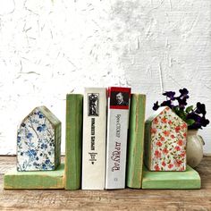 three books are stacked on top of each other in front of a vase with flowers