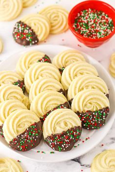 chocolate covered cookies with white frosting and sprinkles are on a plate