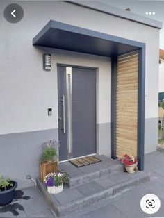 the front door is open and there are potted plants on the steps next to it