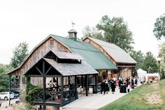 a group of people standing in front of a wooden building with a green roof and steeple