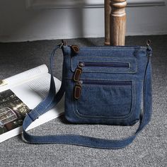 a blue purse sitting on top of a floor next to an open book and magazine