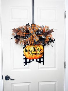 a front door decorated for halloween with an orange and black wreath that says hey there's pumpkin