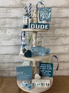 a three tiered display with baby items on it's sides and the words, boy, made out of wood