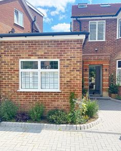 a brick house with white windows and shutters