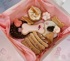 a box filled with lots of different types of donuts and cookies on top of pink paper