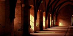 the sun is shining down on an old building with arches and columns, along with stone flooring