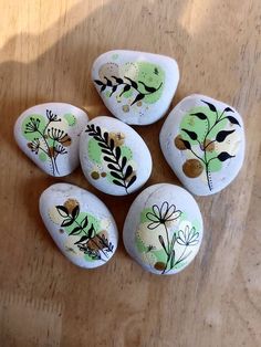 six painted rocks sitting on top of a wooden table