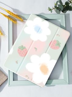 an ipad case with flowers and strawberries painted on the side, next to a plant