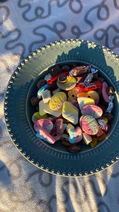 a bowl filled with assorted candies on top of a white and blue table cloth