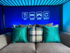 a couch with some pillows on top of it in front of a blue wall that says eat sleep game repeat