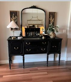 a black dresser sitting in front of a mirror on top of a hard wood floor