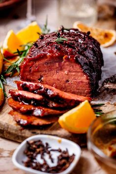 a large meat is sitting on a cutting board with lemons and rosemary garnish