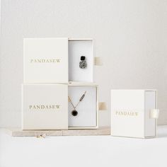 three jewelry boxes with necklaces in them sitting on a white table next to each other