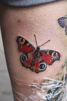 a small butterfly tattoo on the side of a woman's leg with blue eyes