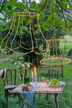 an outdoor dining table set for two with lights hanging from the ceiling