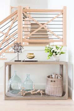 a wooden shelf with vases and other items on it in front of a stair case