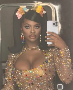 a woman taking a selfie in front of a mirror wearing a gold dress with colorful sequins on it