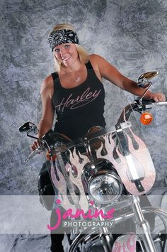 a woman in black tank top sitting on a motorcycle with flames painted on the side