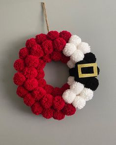 a knitted wreath with santa claus's hat hanging on a wall next to a string