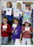 a group of children holding up their drawings