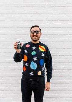 a man in a black sweater with planets and stars on it holding up a camera