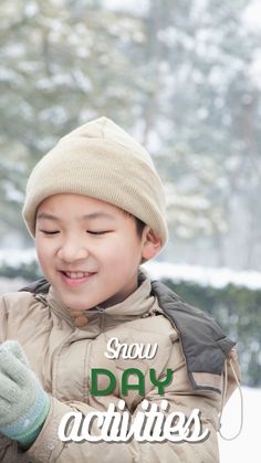 a young boy wearing a hat and mittens smiles while looking at his cell phone