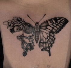 a woman's chest with a butterfly and flowers tattoo on her back, which is black and white