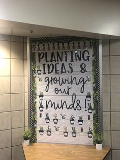 a bulletin board with plants and writing on it in front of a wall mounted planter