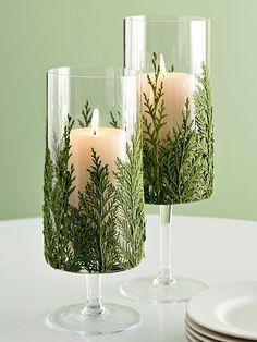 two glass vases with candles in them sitting on a table