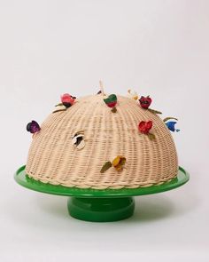 a wicker cake stand with flowers on it's top and green base, against a white background