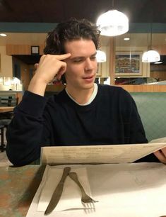 a young man sitting at a table with a piece of paper in front of him