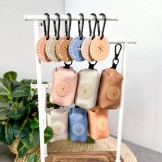 a rack with several small purses hanging from it's hooks and some plants in the background