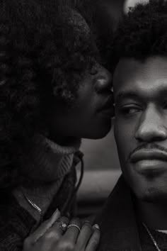 a black and white photo of a man kissing a woman's forehead with her eyes closed