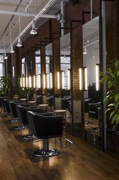 an empty salon with chairs and plants in the corner, along with mirrors on the wall