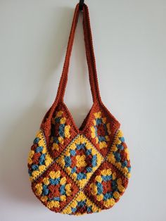 a crocheted bag hanging on a wall with a hook in the middle that is attached to it