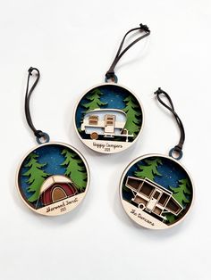 three ornament shaped like campers with trees in the background