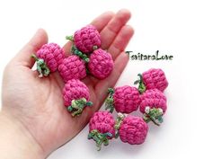 small pink crocheted flowers sitting in the palm of someone's hand