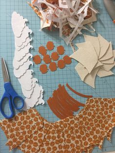 paper cut outs and scissors on a cutting board with crafting supplies laid out around them