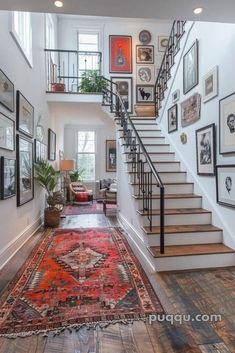 a staircase leading up to a living room with lots of pictures on the wall and rug